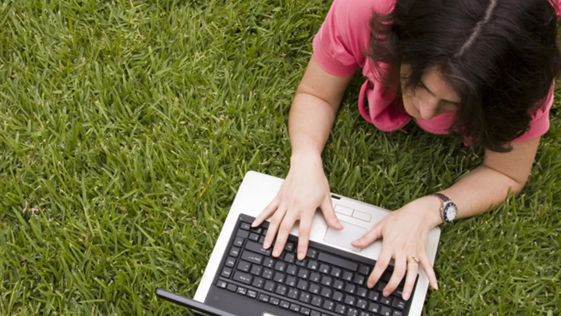 Kvinne jobber på PC på grønt gress