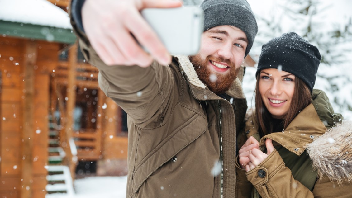 Par tar selfie utenfor hytte i snøvær