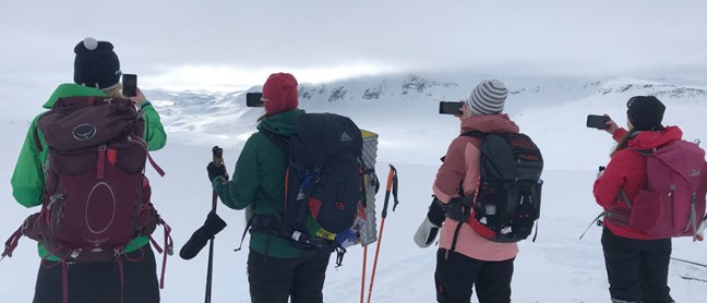 Fire mennesker som tar bilde av naturen på fjellet.