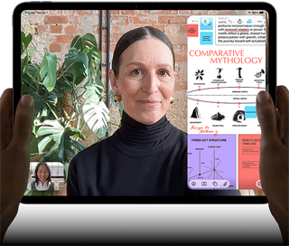 En iPad Pro i fargen stellarsvart vises forfra i liggende retning. Enheten har avrundede hjørner og svart kant rundt skjermen. Den holdes av hender på venstre og høyre side. Skjermen viser en FaceTime-samtale som oversettes direkte, og en lærerik app viser en presentasjon av «Comparative Mythology» med tekst, diagrammer og håndskrevne notater.